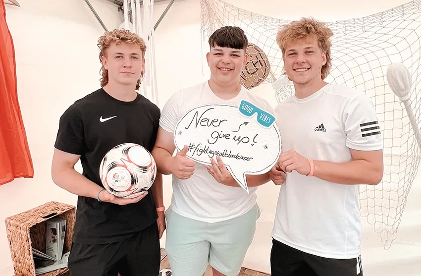 Junge Fußballbegeisterte halten ein inspirierendes Schild mit der Aufschrift 'Never Give Up' bei einem Workshop des VKS während des Bundesfinales der Soccer Liga auf Rügen