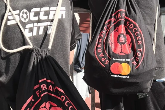 Fußballbegeisterte mit Rucksäcken, die das Logo der Soccer City und das Markenzeichen der Sparkassen Fairplay Soccer Tour tragen