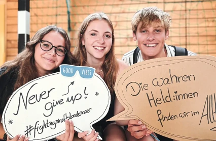 Schüler des Johann-Gottfried-Herder-Gymnasiums in Pirna halten ermutigende Schilder hoch, die zu Positivität und Durchhaltevermögen im Kampf gegen Blutkrebs während einer Typisierungsaktion aufrufen